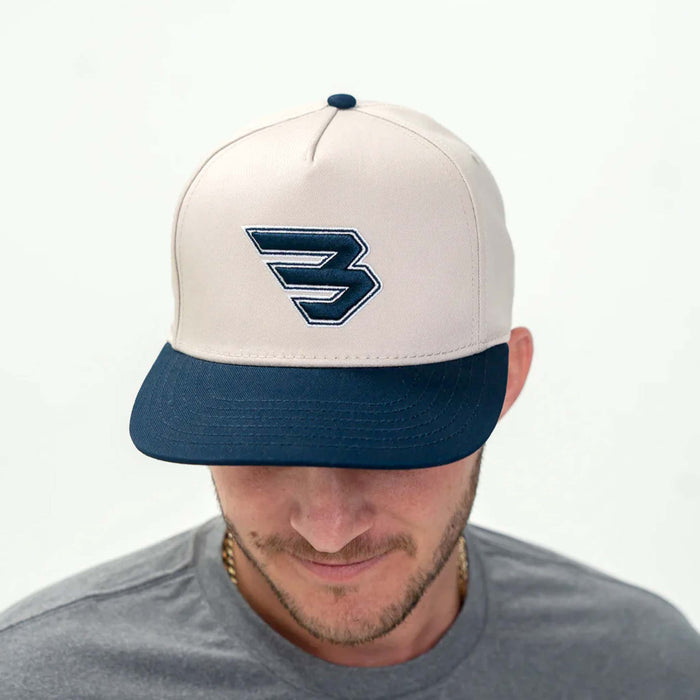 Cream high-profile 5-panel snapback cap with embroidered Flying B logo on front.