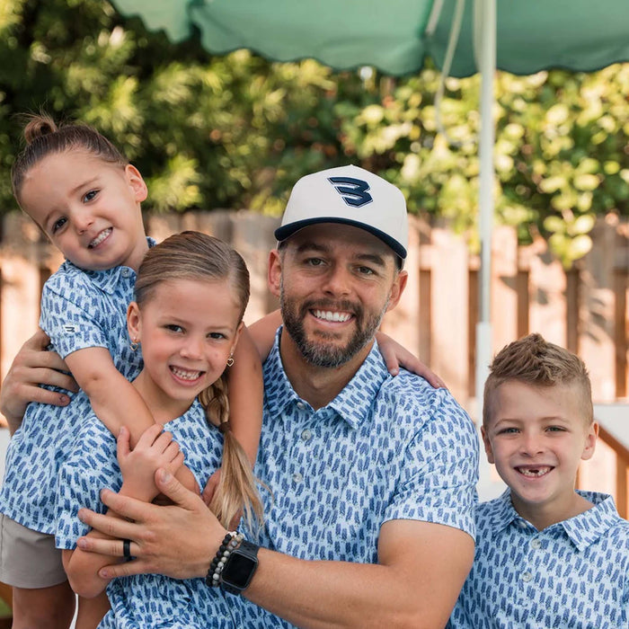 Man wearing Cream high-profile 5-panel snapback cap with embroidered Flying B logo on front, while posing for a photo with his kids.