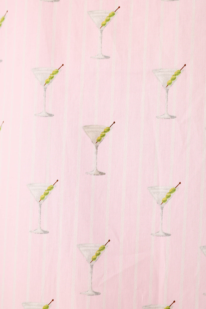 Close up of a pink and white striped fabric with a repeating pattern of martini glasses with 3 green olives.