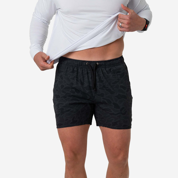 Person wearing black patterned shorts on a white background