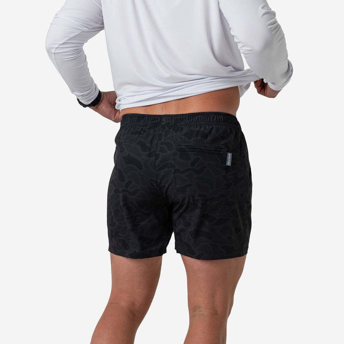 Person wearing black patterned shorts on a white background