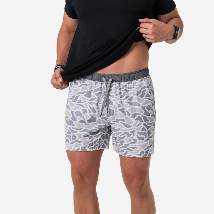 Person wearing gray camouflage shorts on a white background