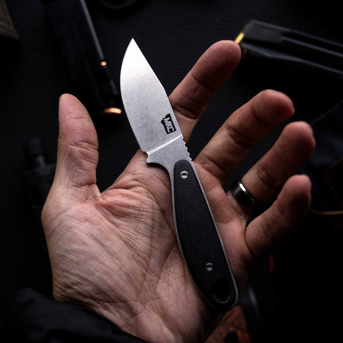 Compact BADROCK knife in black, held in a hand, showcasing its sleek design and durable handle.