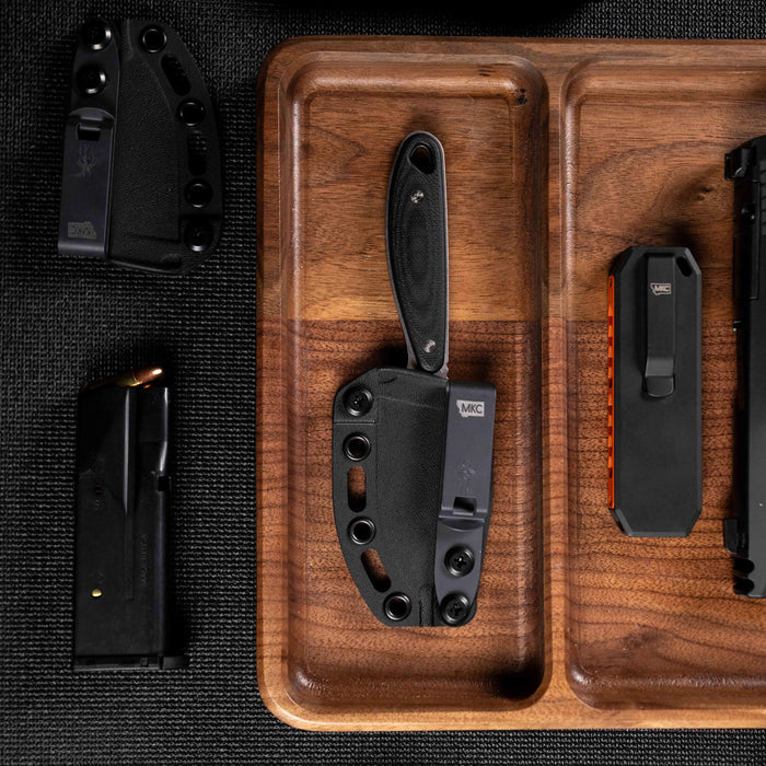 BADROCK knife in black on a wooden tray with other tools, showcasing its durable design for outdoor and tactical use.