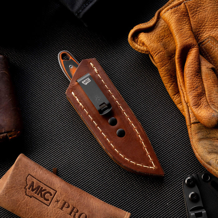 Badrock leather sheath with concealed pocket carry feature, surrounded by leather gloves and tools, showcasing craftsmanship.