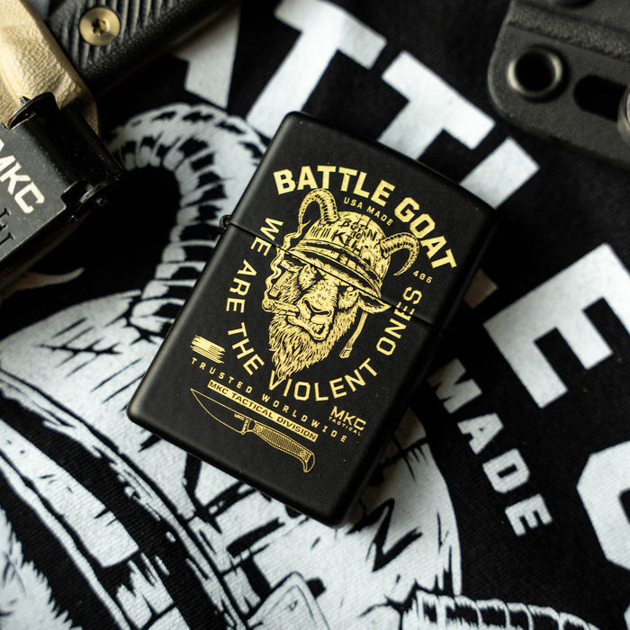 Black Zippo lighter featuring a lion graphic and "BATTLE GOAT" text, resting on a tactical shirt background.