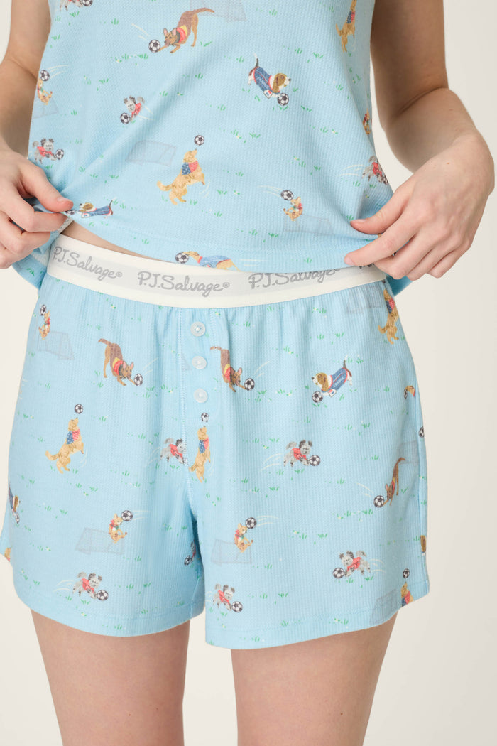 Light blue fabric with playful dog and soccer ball prints; soft, smooth texture; features branded waistband detailing.