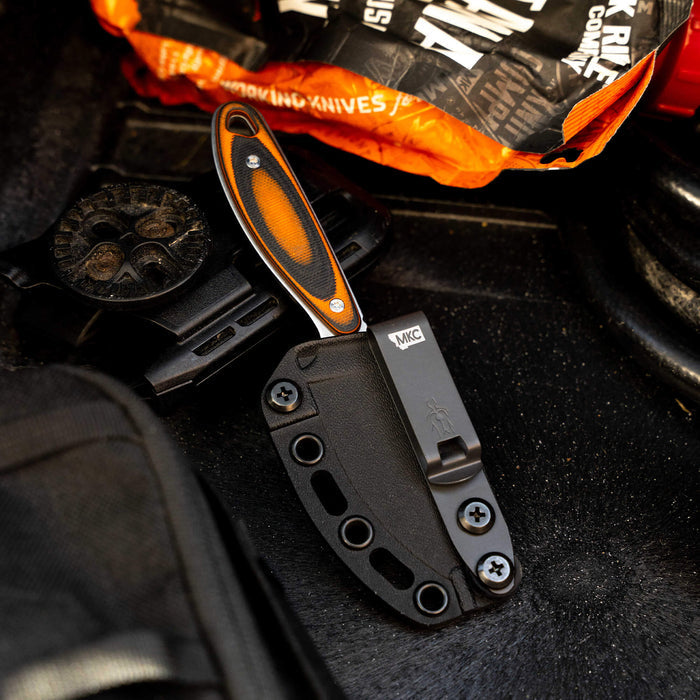 Kydex sheath for Castle Rock knife, featuring a secure fit and durable design, placed on a textured surface with gear.