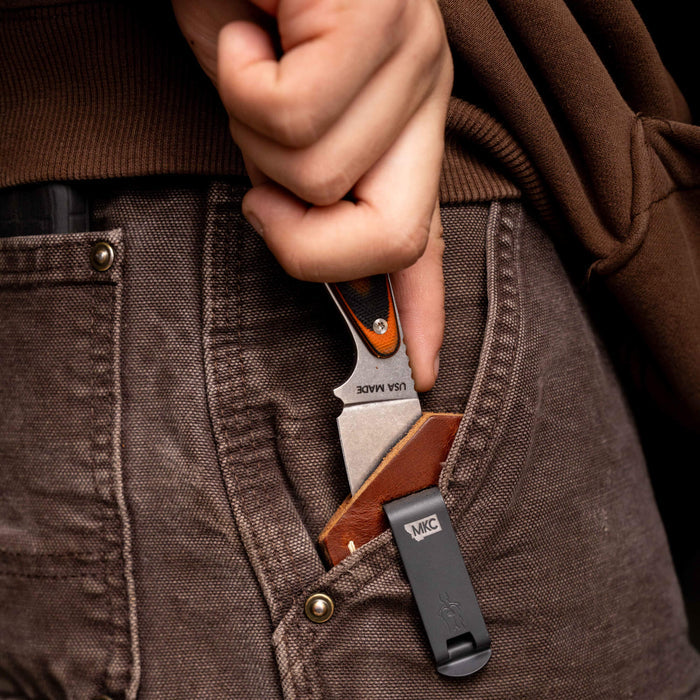 A person discreetly retrieving a knife from a Castle Rock leather sheath tucked in their pocket, showcasing concealed carry functionality.