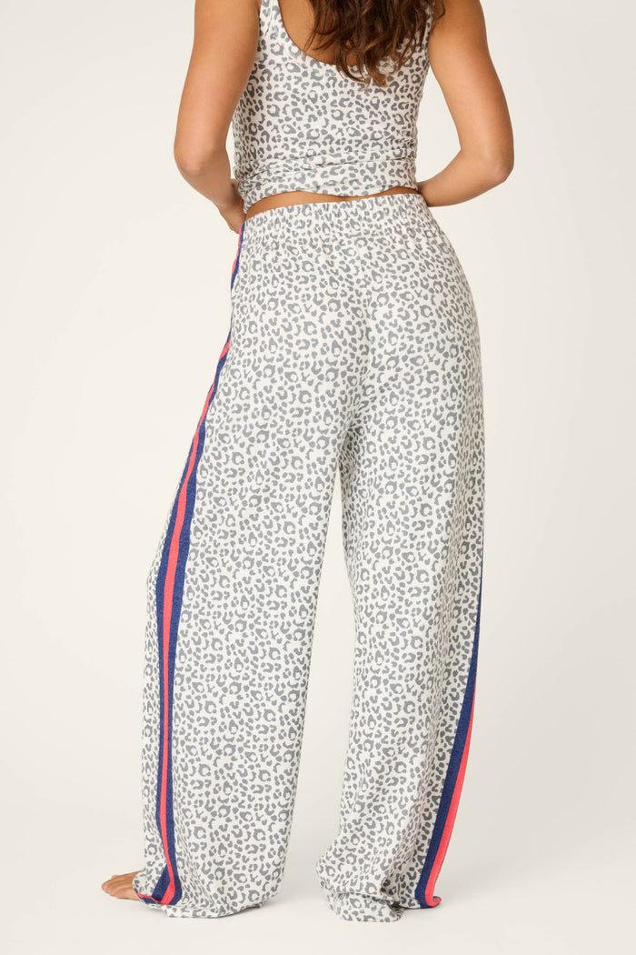 A woman models the Cat’s Meow Big Stretch Pajama Pants by P.J. Salvage—loose, high-waisted leopard print with blue and red stripes in peachy-soft jersey—paired with a matching sleeveless crop top for cozy nights in.