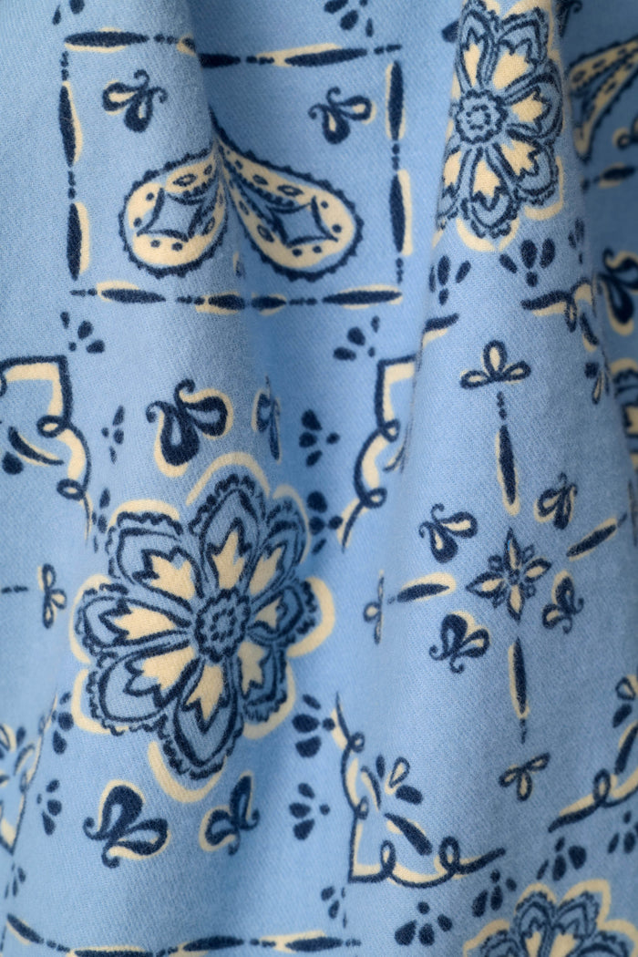 A close-up of a light blue fabric with a navy blue and cream paisley and floral pattern.