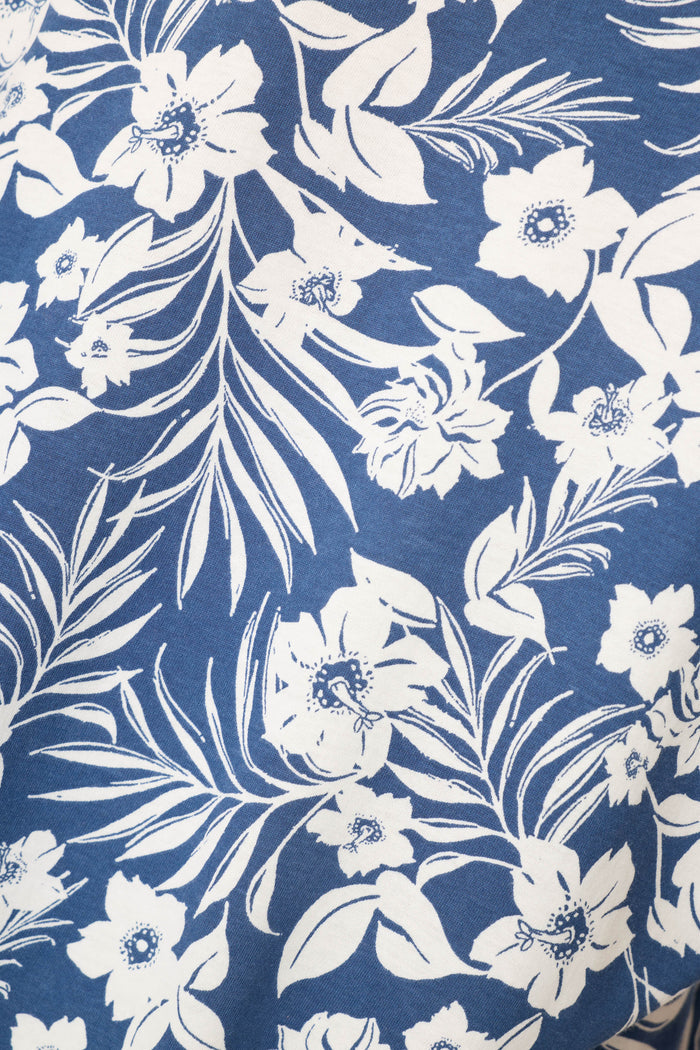 The P.J. Salvage Cotton Jersey Midnight Garden Cropped PJ Set features white floral and leaf motifs on a blue background, offering a decorative botanical design.
