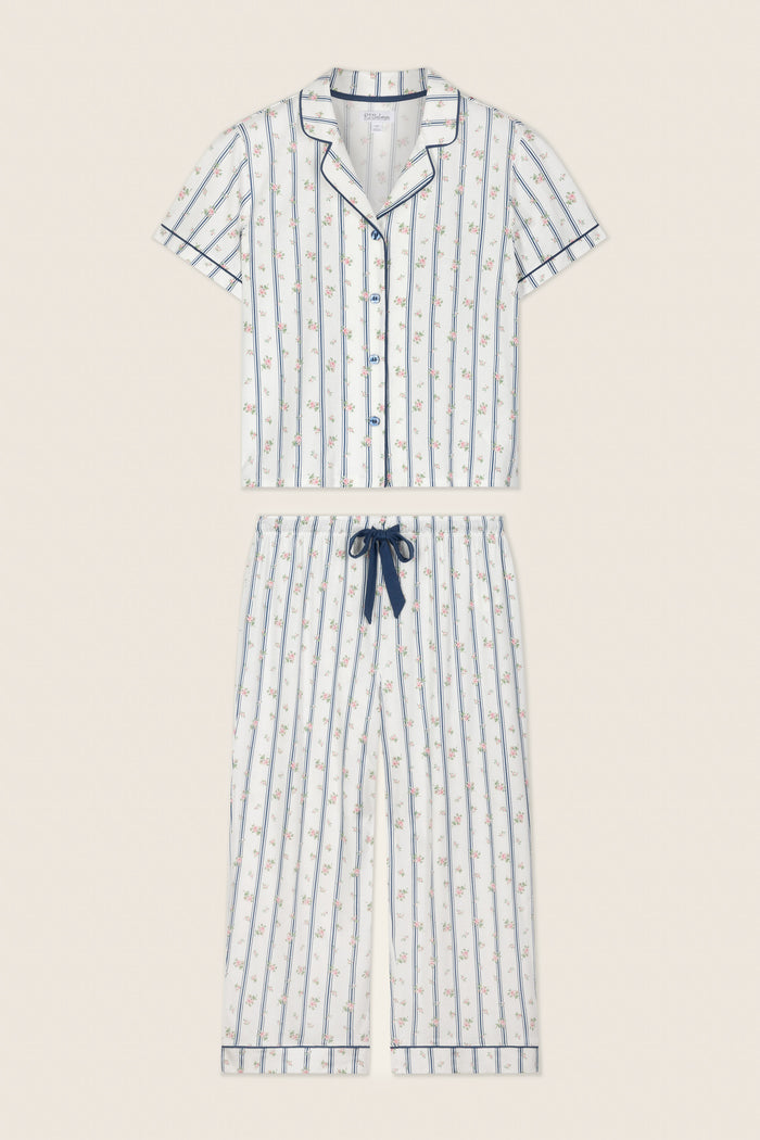 The P.J. Salvage Cotton Jersey Stripes & Blooms Cropped PJ Set features a short-sleeve button-up top and drawstring pants in white with vertical blue stripes, floral print, and navy piping along the edges.