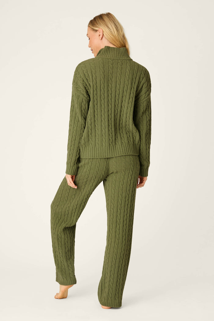 A person stands barefoot facing away, wearing the Cozy Chenille Cable Knit Olivine Pullover Lounge Set by P.J. Salvage against a light background.