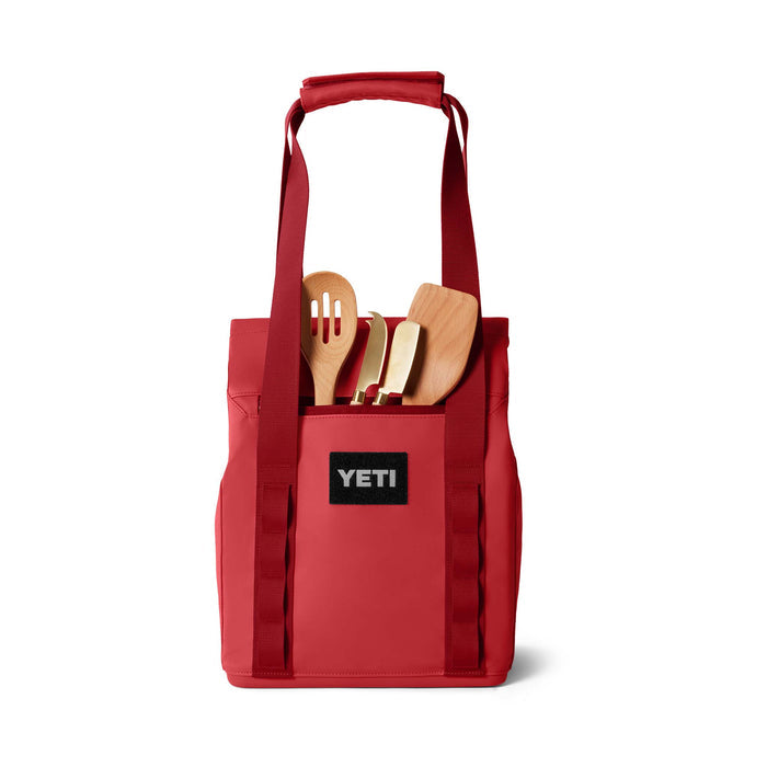 Front view of the tote filled with wooden grilling tools in the outer pocket, showing black YETI patch logo.