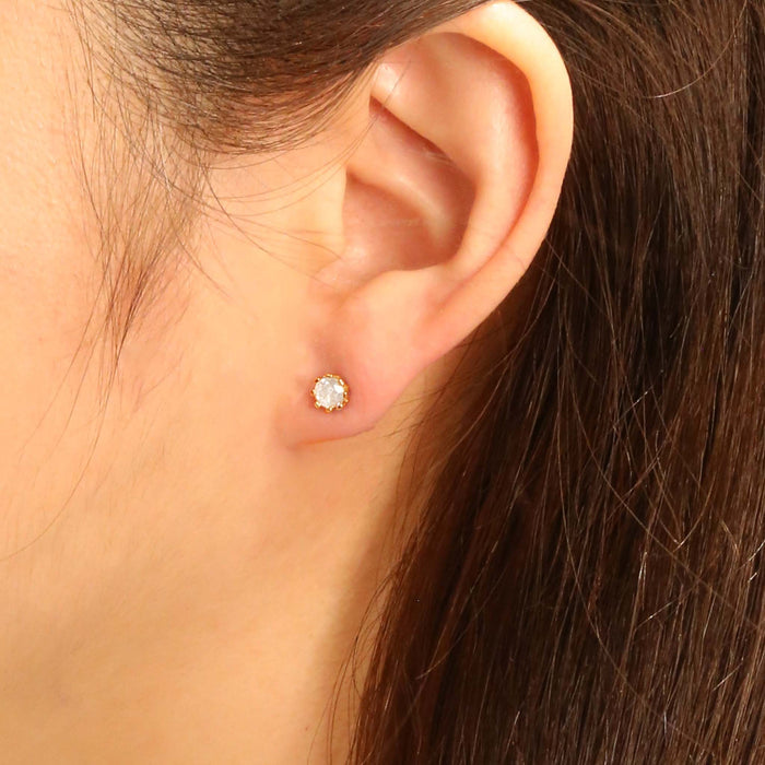 Do Everything In Love Diamond Stud Earrings, Close-up of a woman wearing a classic gold solitaire stud earring with a round clear stone in a claw setting.