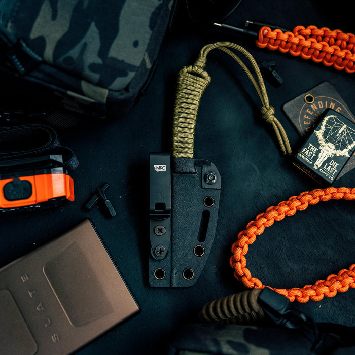 Discreet Carry Pocket Clip positioned among tactical gear, showcasing its sleek design and practical functionality.