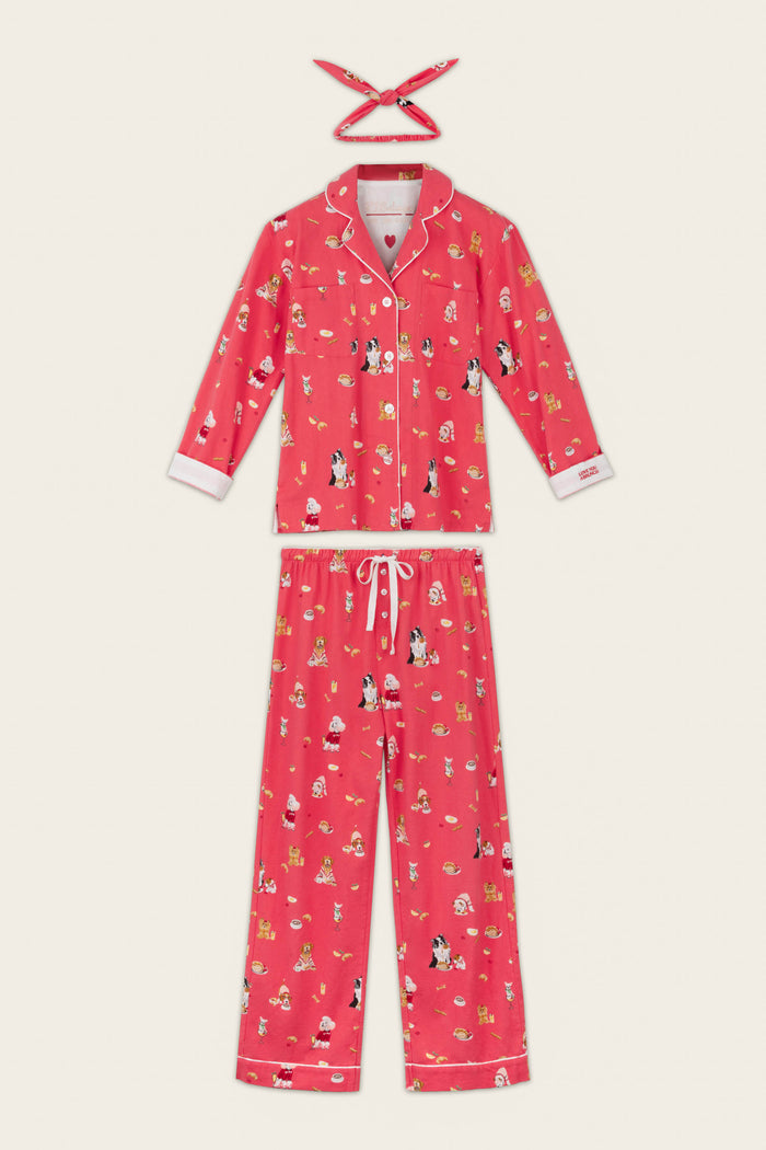 The P.J. Salvage Dogs Who Brunch Print 3-Piece Long Sleeve Flannel PJ Set includes a long-sleeve, red pajama top and pants crafted from soft cotton flannel, adorned with playful cartoon dog and floral prints. A matching red headband is included above the set. Crisp white piping accents the collar, cuffs, and hems, making this a cozy option for matching dog owner pajamas.