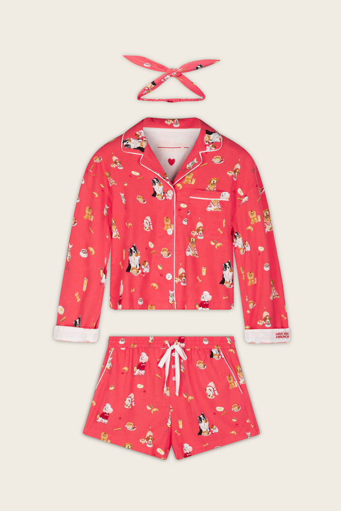 P.J. Salvage’s Dogs Who Brunch Print 3-Piece Flannel PJ Set features a playful dog and food print on cozy cotton flannel, including a long-sleeve button-up top, matching drawstring shorts, and a coordinating headband—all presented against a neutral background.