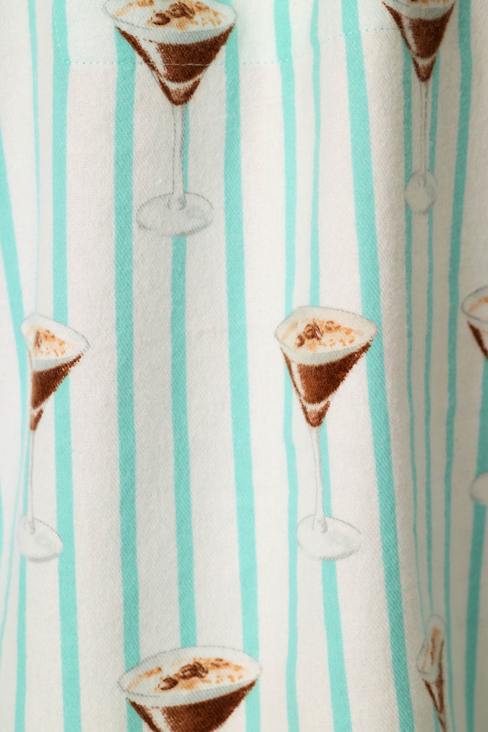 A close-up of a white fabric with vertical light blue stripes and an allover print of espresso martinis.