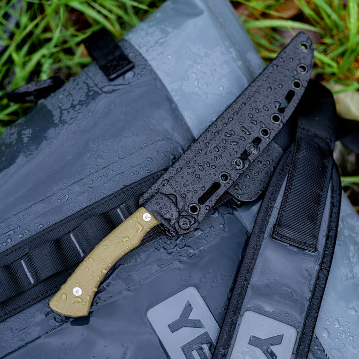 Montana Knife Company's Flathead Fillet knife with Kydex sheath resting on a waterproof bag, showcasing its rugged design.