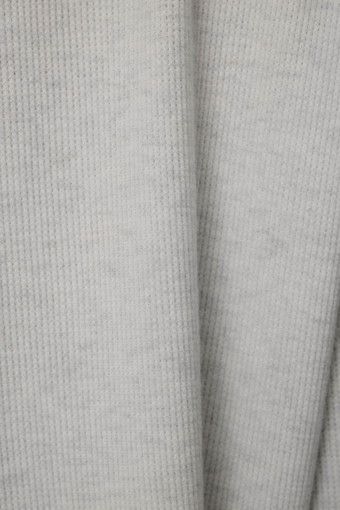 Close-up of a light gray knit fabric with a soft waffle texture.