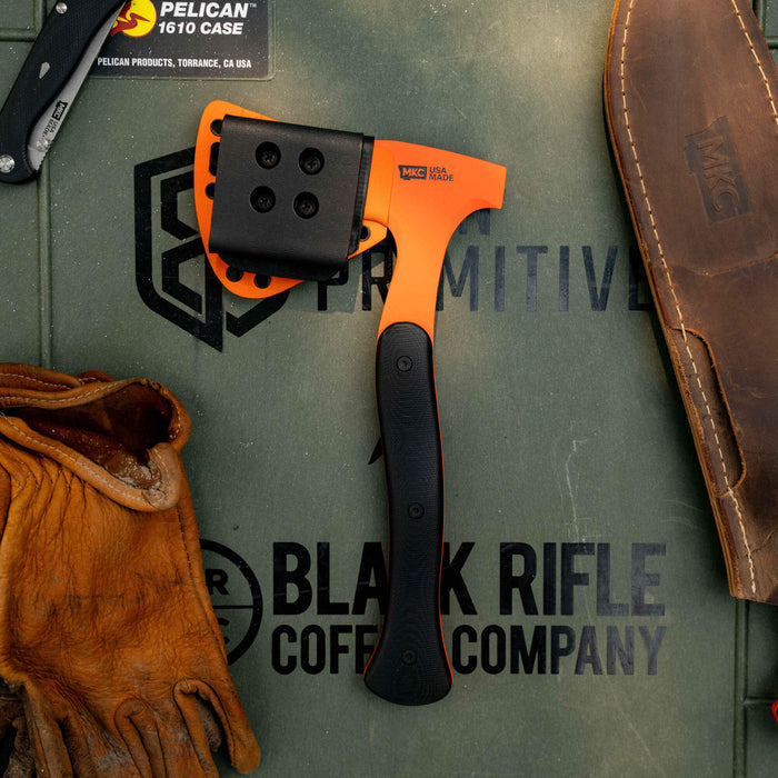 HELLGATE HATCHET with additional Kydex sheath on a textured surface, surrounded by gloves and tools, showcasing its rugged design.