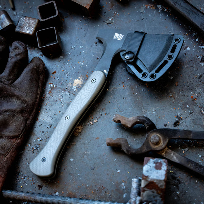 Montana Knife Company's Hellgate Hatchet with Kydex sheath on a workbench surrounded by tools and debris.