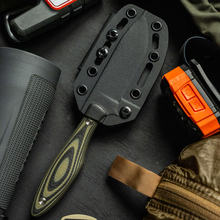 JACKSTONE knife with a green and black handle, displayed with tactical gear and accessories on a dark surface.