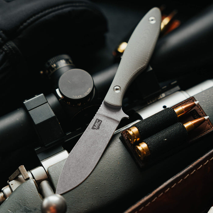 JACKSTONE knife in grey resting on a rifle, showcasing its sleek blade and ergonomic handle, ideal for outdoor use.