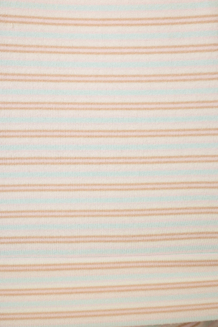 Close up of fabric featuring thin pink & blue stripes on a white background.