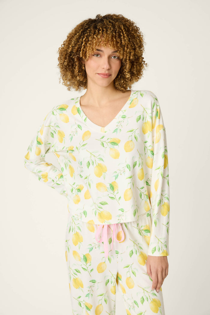 Yellow lemons and green leaves scattered on white fabric with a textured look and a contrasting pink drawstring detail.