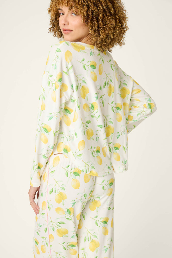 Fabric with a yellow lemon and green leaf print on a light background, giving a fresh, vibrant pattern.
