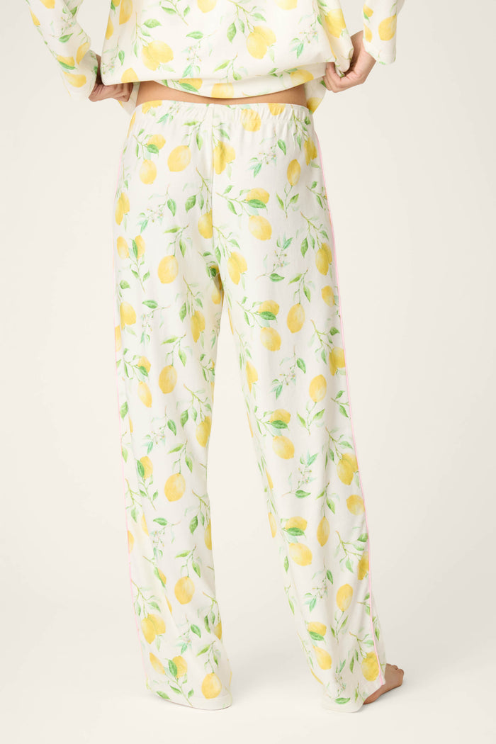 Yellow lemon and green leaf print on a soft white fabric, set against a plain, light background.
