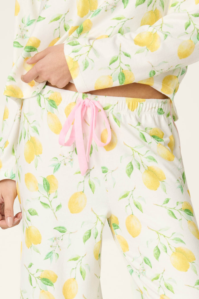 White fabric with a yellow lemon and green leaf pattern, accented by a pink ribbon.