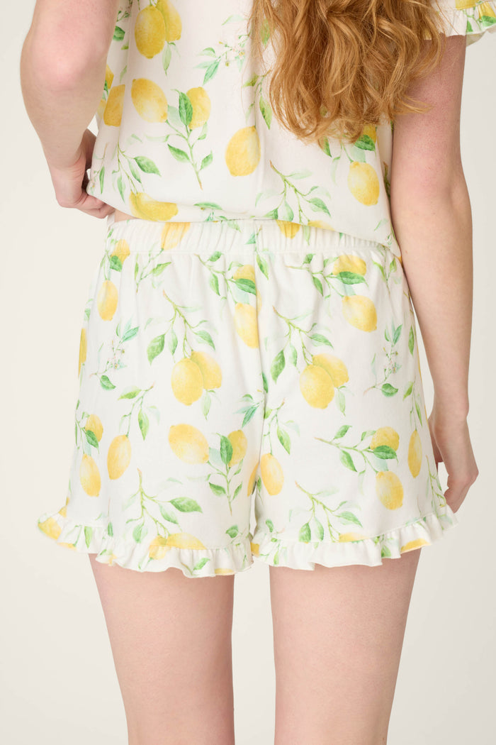 White fabric with yellow lemon and green leaf prints, elastic detailing, and ruffled edges.