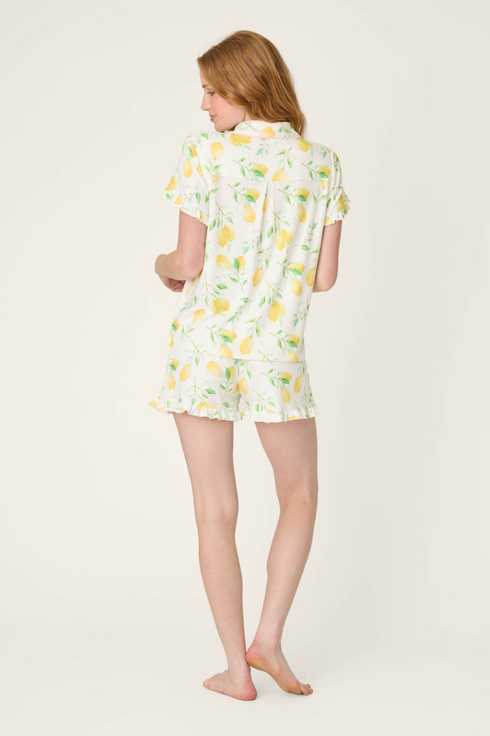 White fabric with a vibrant lemon print and ruffled edges, displayed against a plain light background.