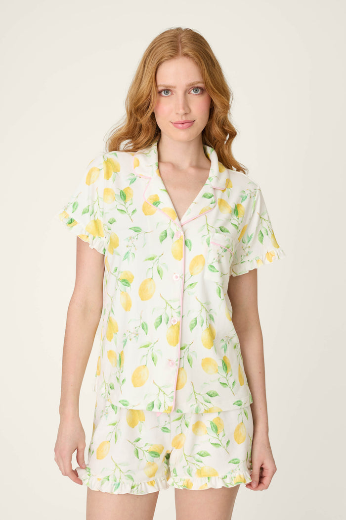 White fabric with a playful lemon and green leaf print, soft texture, and subtle ruffled detailing.