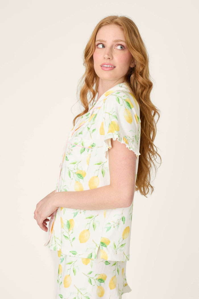 Fabric with a lemon and leaf print in bright, fresh colors, set against a light background.