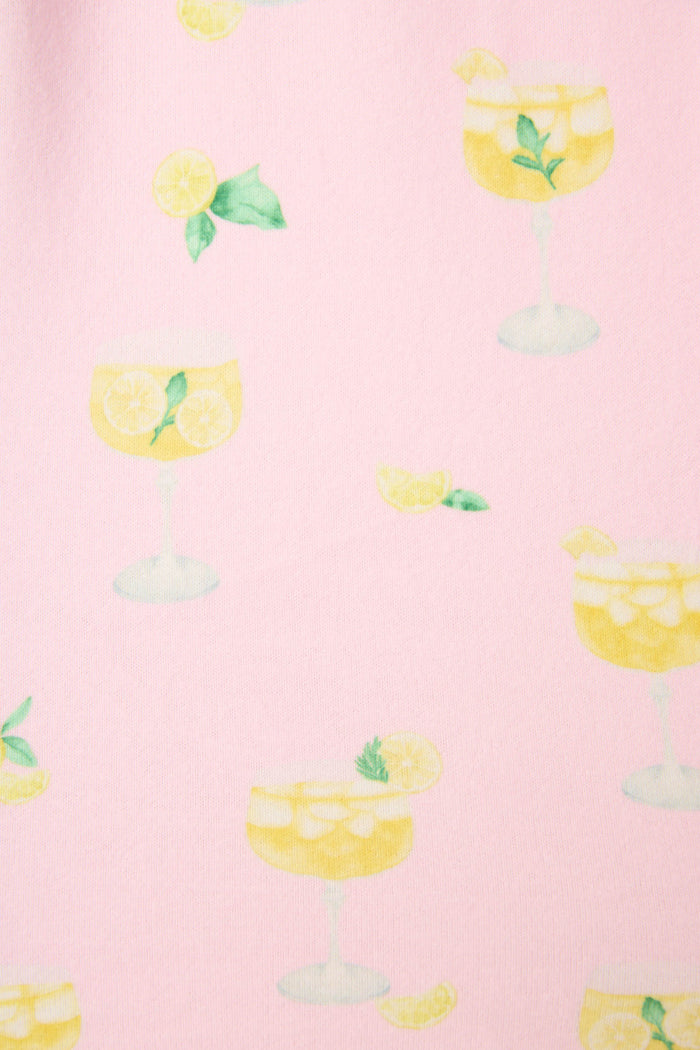 Pattern of illustrated yellow drinks with lemon slices, mint leaves, and ice on light pink, with scattered lemon wedges and mint.