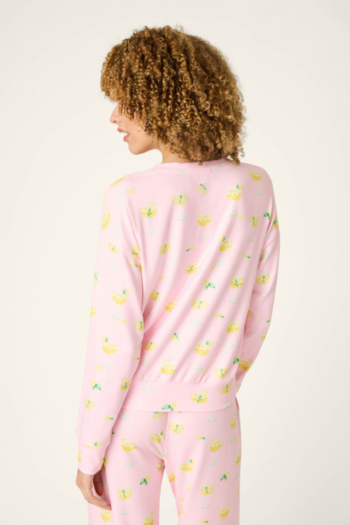 Fabric with a playful yellow pattern on a light pink background, shown against a plain, light setting.