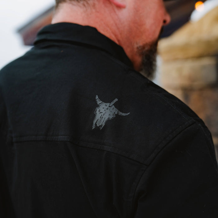 Black long sleeve shirt featuring a pearl snap design and a subtle graphic of a bull skull on the back.
