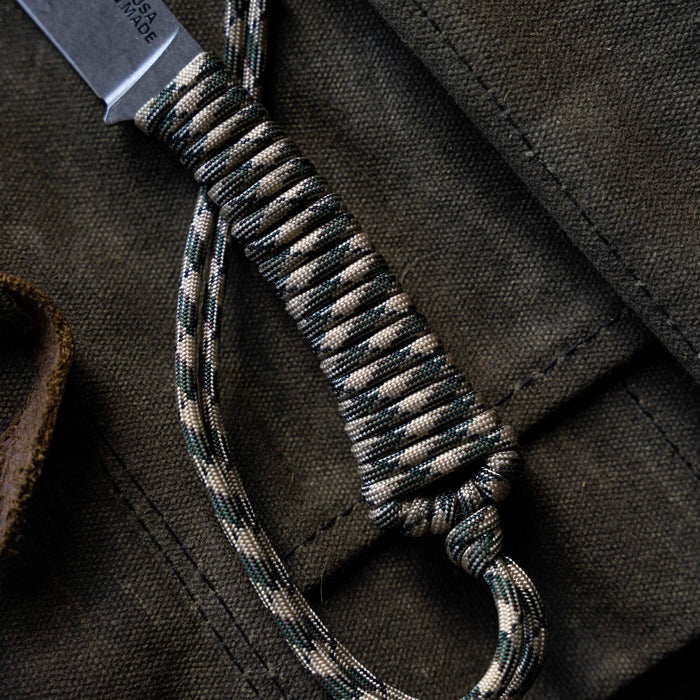Close-up of the Mini Stoned Goat knife handle in desert camo, featuring a durable paracord wrap for a secure grip.