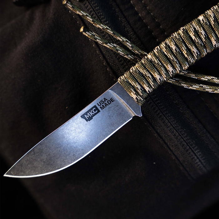 Mini Stoned Goat knife in forest camo with a durable blade and paracord handle, designed for outdoor use.