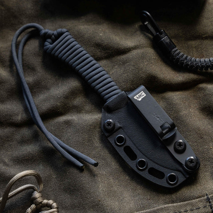 Mini Stoned Goat knife in grey with a textured handle and sheath, designed for outdoor and tactical use.