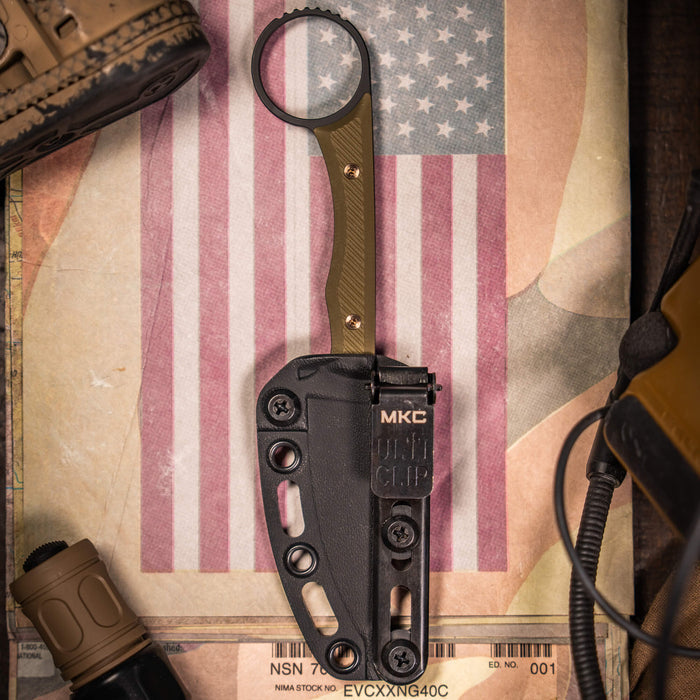 Mini Wargoat knife in black and olive drab with sheath, placed on a vintage map and American flag backdrop.