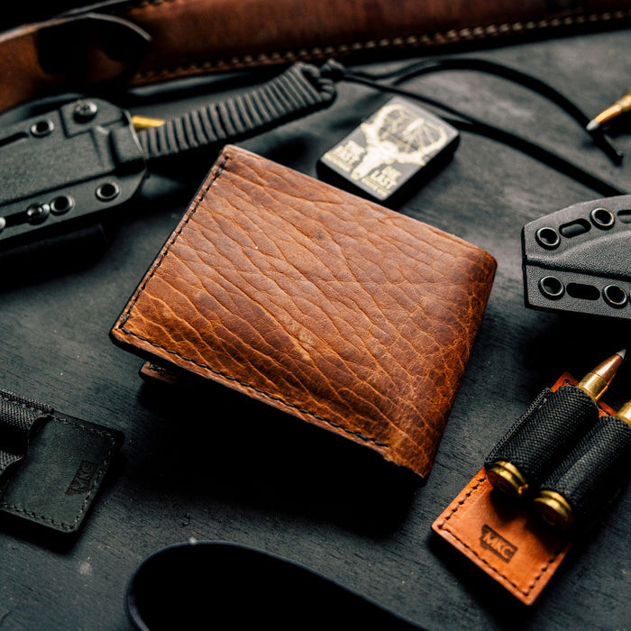 MKC Bison Skull leather wallet surrounded by tactical gear and accessories, showcasing its rugged design and craftsmanship.