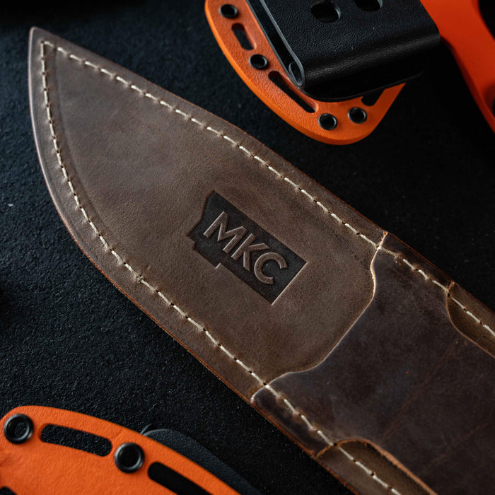 Close-up of the MKC Chopper leather sheath featuring a stamped logo and detailed stitching, designed for durability.