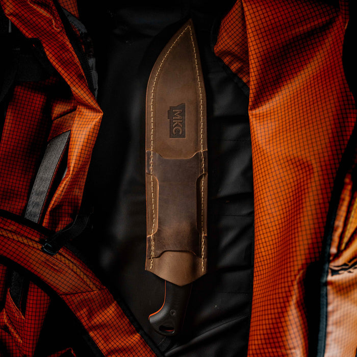 MKC Chopper leather sheath displayed inside an orange backpack, showcasing its durable design for outdoor use.