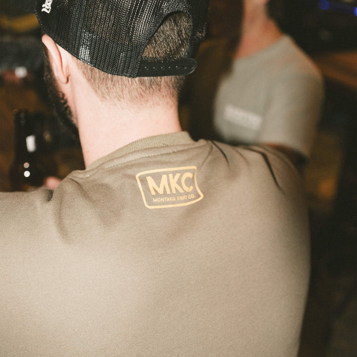 Olive MKC crewneck sweatshirt featuring a logo on the back, ideal for outdoor enthusiasts and working professionals.